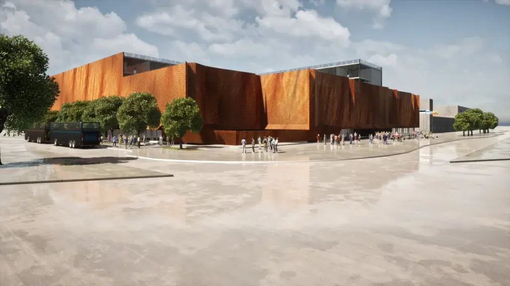 Inimesed kõnnivad modernse oranži lainelise fassaadiga hoone ees, mille kõrval seisab buss.