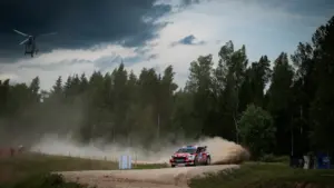 WRC ralliauto kihutamas kruusateel koos taustal oleva helikopteriga Eestimaa looduses.