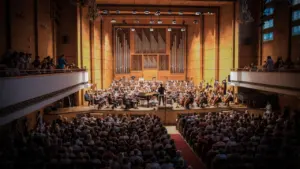 Suur kontserdisaal orkestriga, mida vaatab täismaja publik, tähistamas õpilasmaleva juubelit.