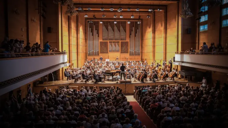 Suur kontserdisaal orkestriga, mida vaatab täismaja publik, tähistamas õpilasmaleva juubelit.