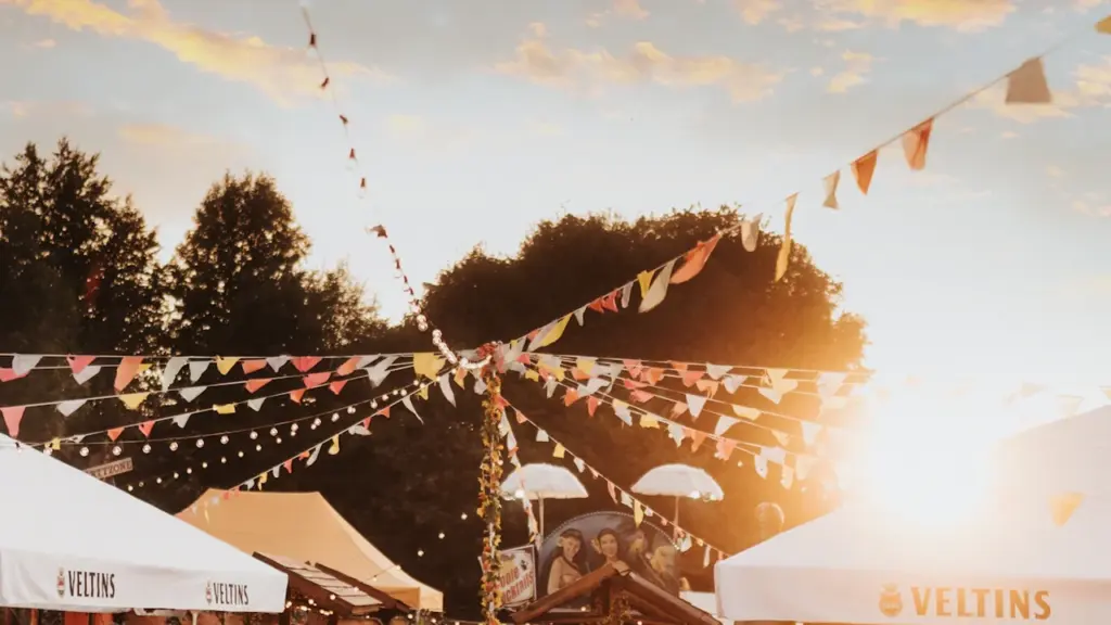 Õhtupäikeses festivaliala, kus on valged telgid ja dekoratiivsed lipud õues.