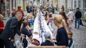 Pikk pikk laud on kaetud vanalinna tänaval, kus inimesed istuvad ja einestavad koos.