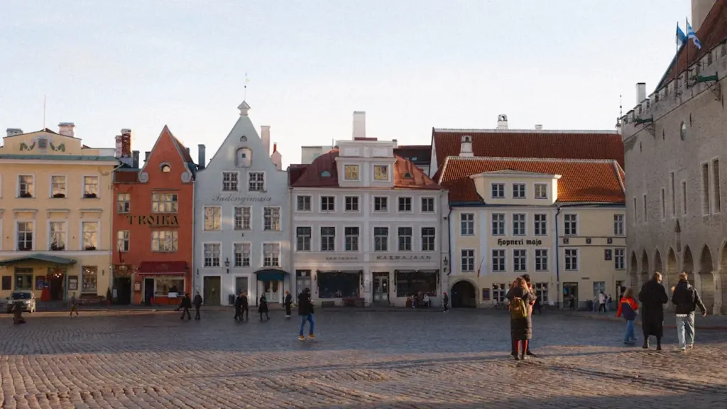 Inimesed kõndimas ajaloolisel munakivitänaval Tallinna vanalinnas päikeselisel päeval, esindades kogukonda ja kaasatust.